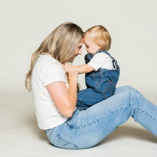 Woman holding a child against a plain background